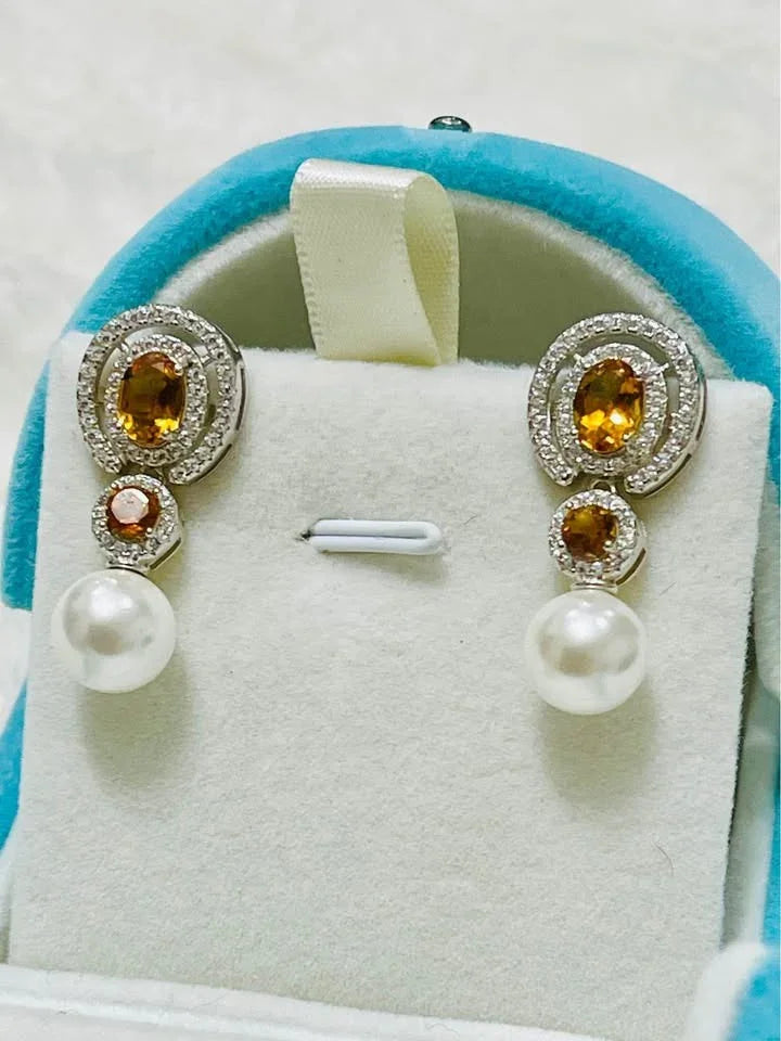 Natural sterling silver dangle earrings with oval citrine, small citrine, and lustrous pearl on a blue display.