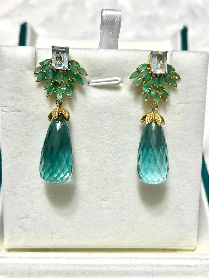 Stunning dangle earrings. The design features large faceted aquamarine drops, emerald leaves, and a central topaz stone.