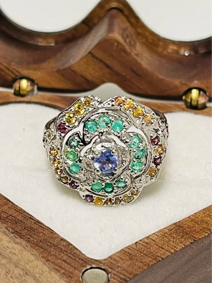 Close-up of a stunning sterling silver flower ring. Features peridot, emerald, and tanzanite.