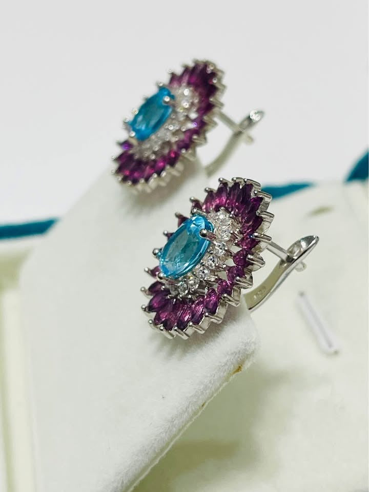 Side view of Swiss blue topaz and rhodolite garnet earrings, showcasing their silver setting and hooks.