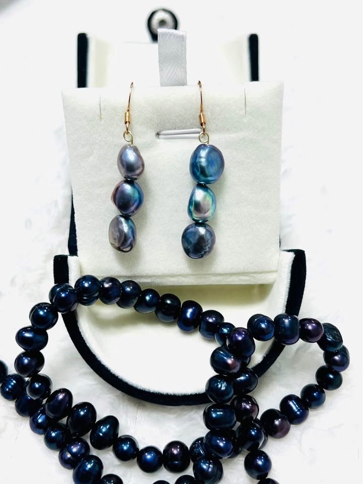 Natural Tahitian black pearl necklace and dangle earrings, showcasing their unique luster and color.