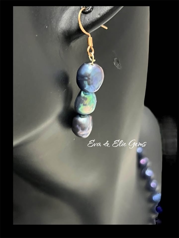 Close-up of a natural Tahitian black pearl drop earring on a mannequin, highlighting iridescent hues.