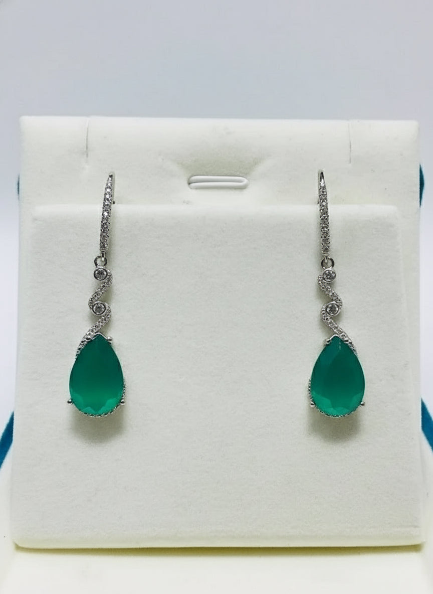 A full-length view of elegant sterling silver earrings with natural green agate teardrop gems on a display.