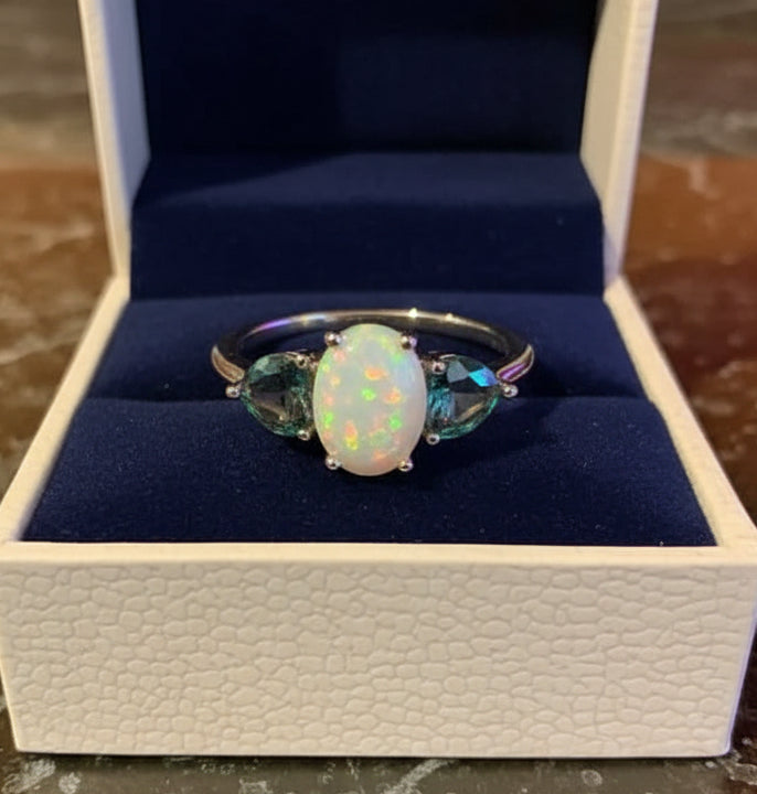 Close-up of a 14K gold-plated three-stone ring with fire opal and mystic topaz, presented in a white box.