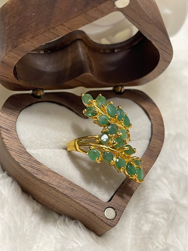 A beautiful sterling silver ring with unheated Colombian emeralds displayed in a unique heart-shaped wooden box.