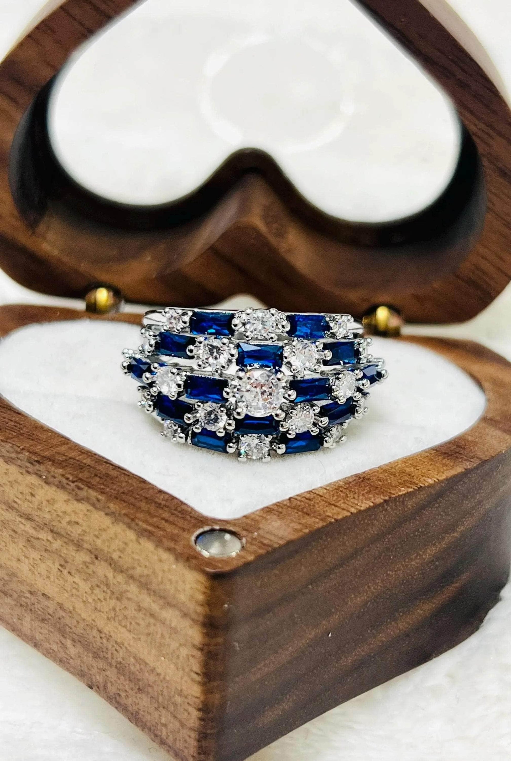 Overhead view of a vintage-inspired sapphire and diamond statement ring in a wooden heart-shaped box.