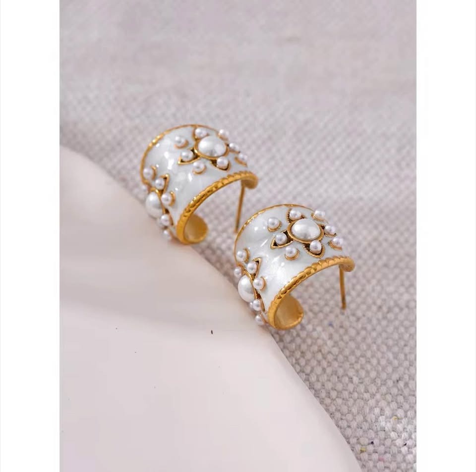 A pair of vintage gold vermeil hoop earrings with white enamel and various sized pearls.