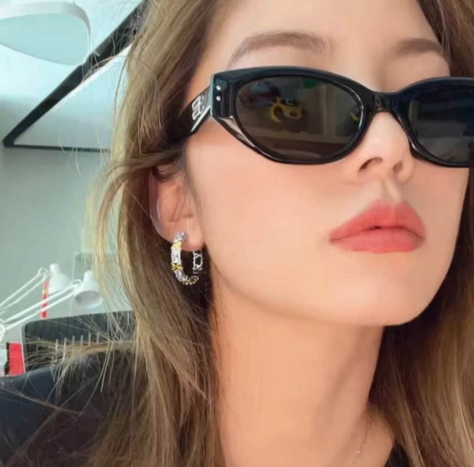 Woman with sunglasses wearing XOXO gold plated silver hoop earrings with cubic zirconia.