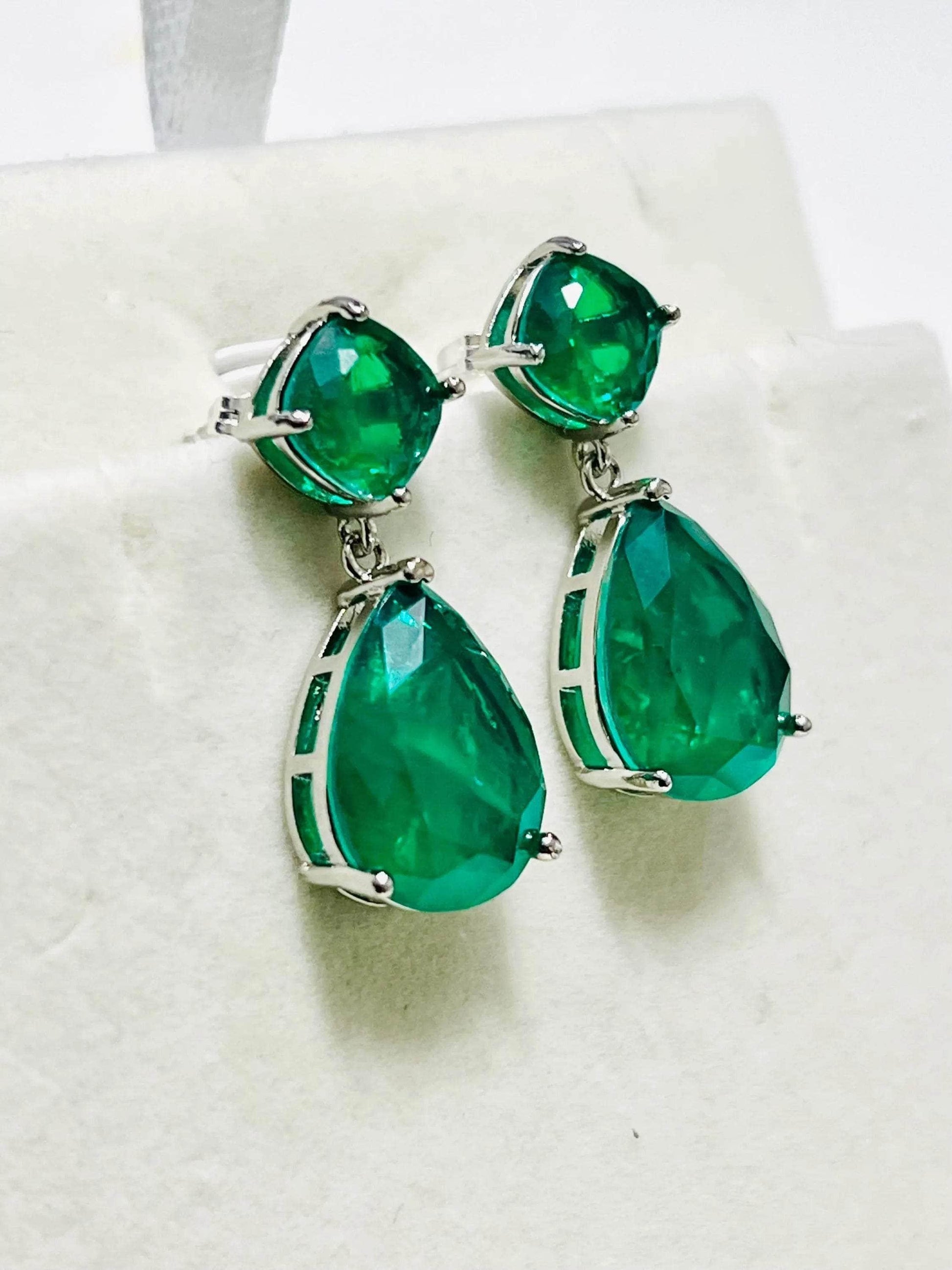 Angled view of exquisite Zambian emerald doublet earrings, showcasing their captivating green color and design.