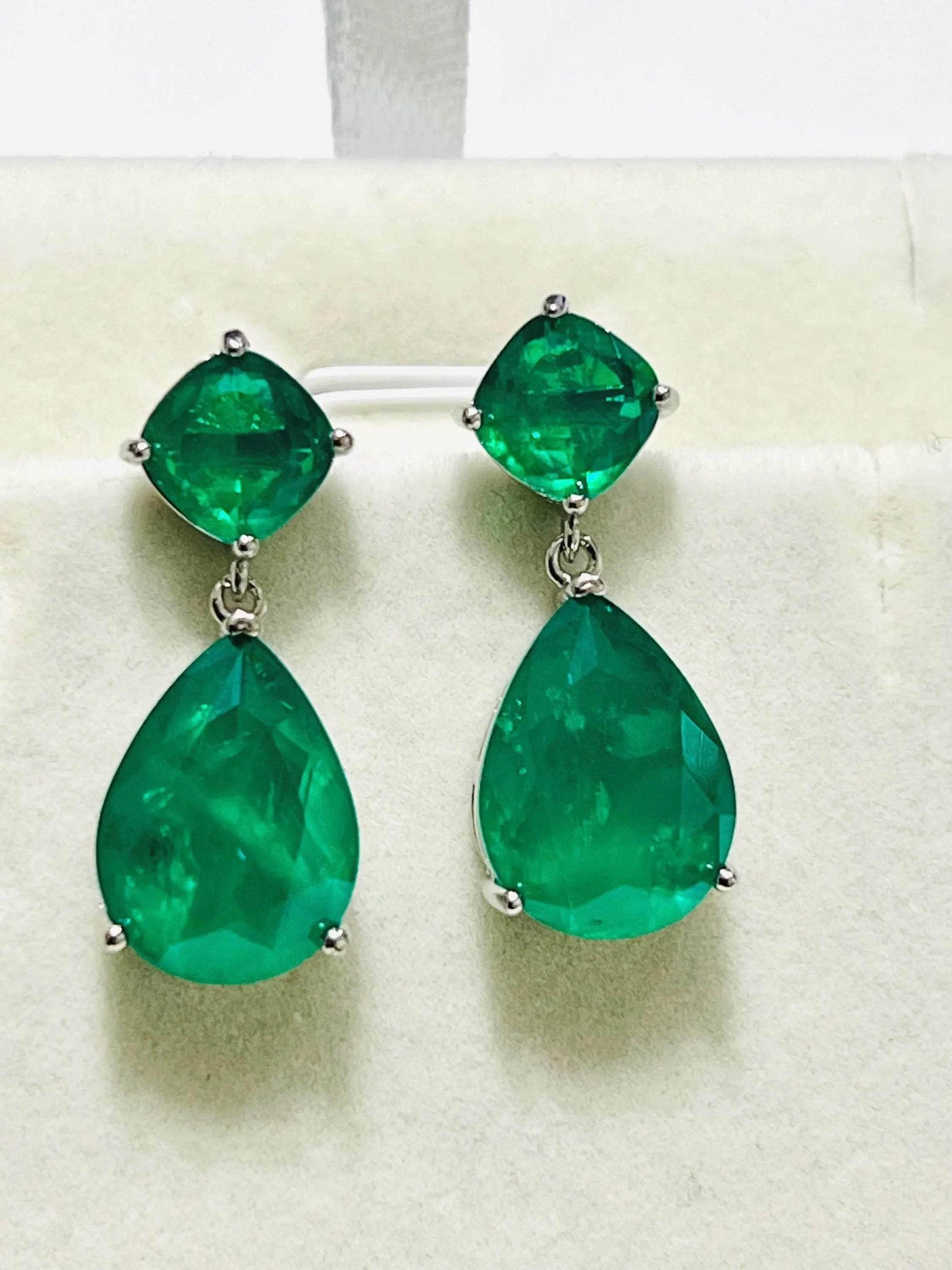 Front view of elegant Zambian emerald doublet earrings with a vibrant green hue, in gold and rhodium.