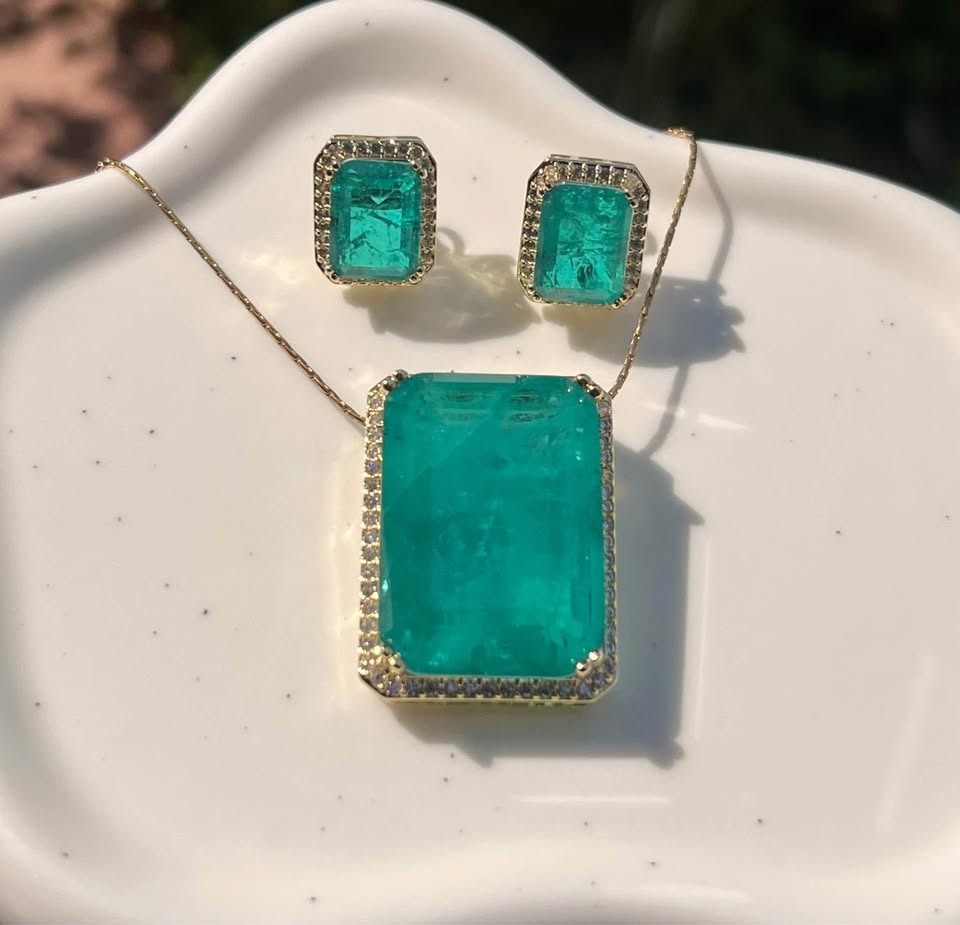 Natural Zambian emerald doublet pendant and earring set with gold accents, on white background.