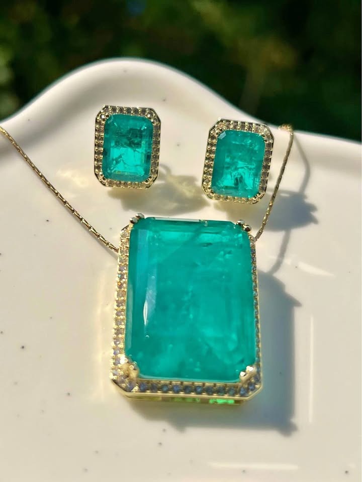 Close-up of natural Zambian emerald doublet pendant and matching earrings, exquisite detail.