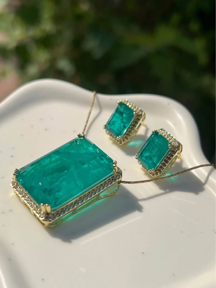 Side angle of a natural Zambian emerald doublet pendant and earrings, showcasing the rich color.