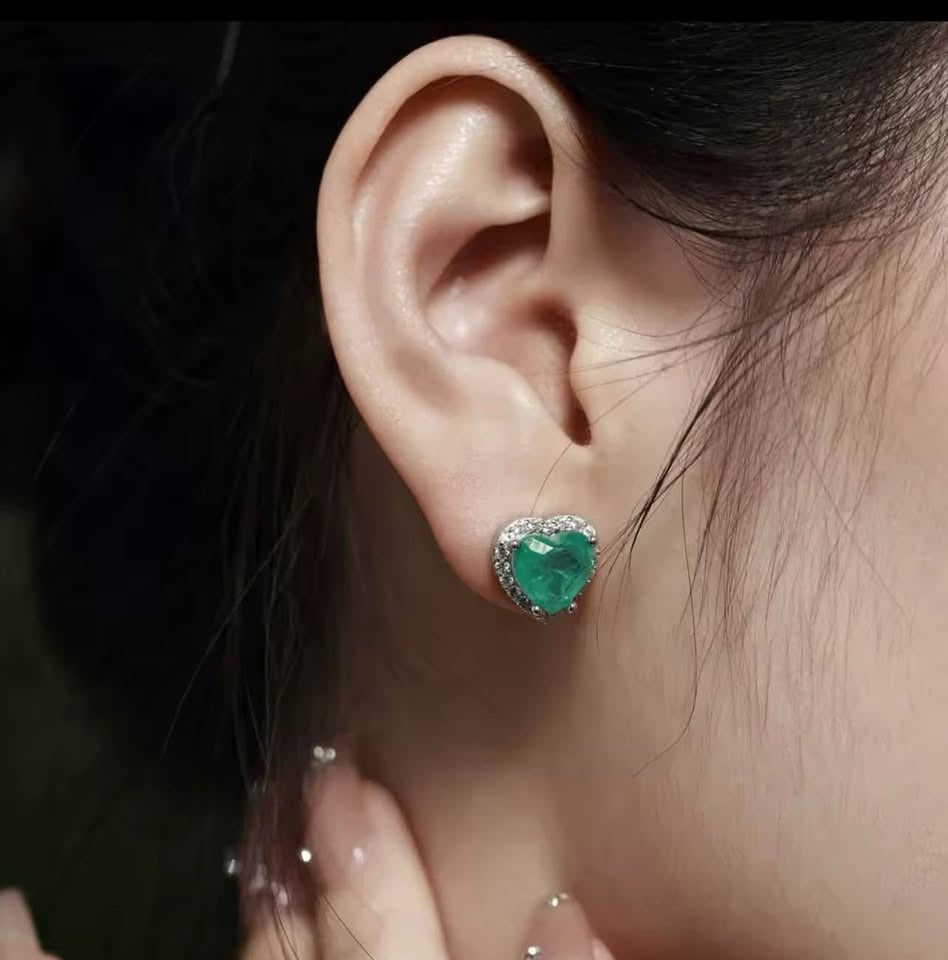  Natural Zambian emerald heart-shaped earring with diamond halo on a woman's right ear.