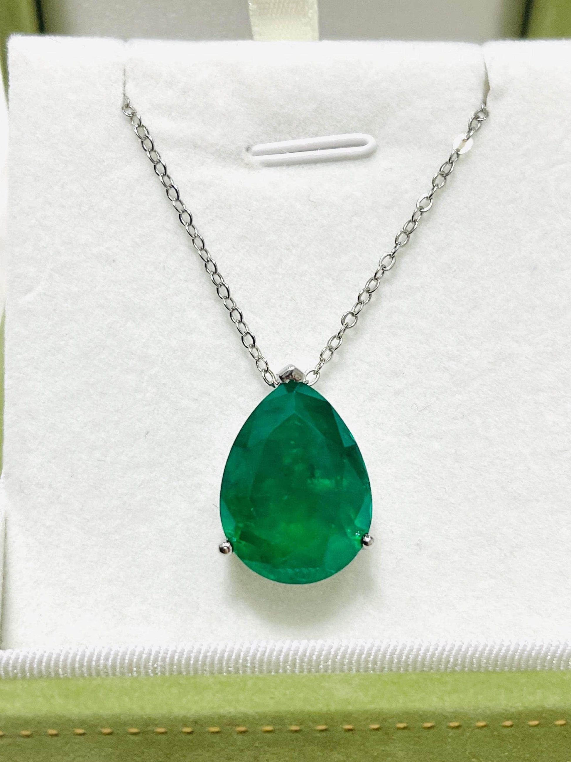 Large pear-shaped Zambian emerald doublet pendant on a silver chain, displayed in a light green box.