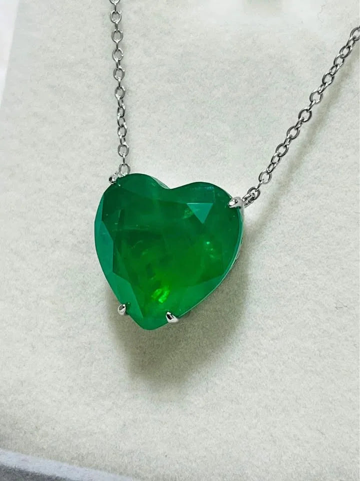Detailed close-up of a faceted Zambian emerald doublet heart pendant on a delicate chain.