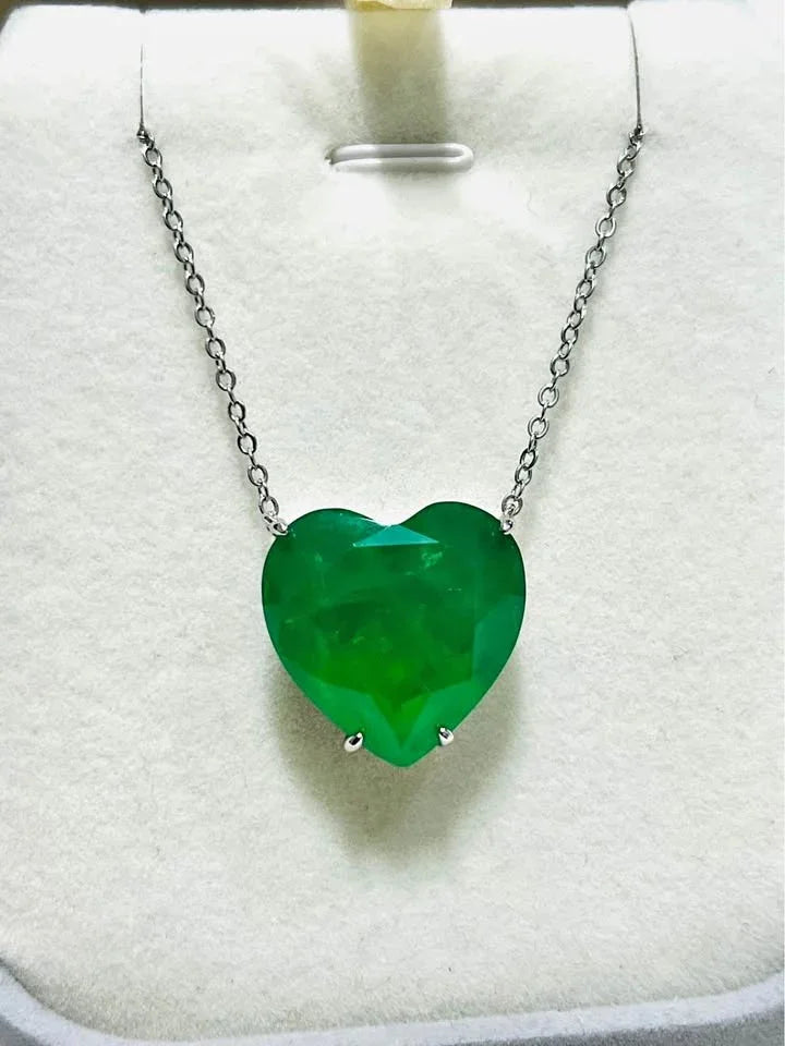 A stunning Zambian emerald doublet heart-shaped pendant necklace on a silver chain, displayed vertically.