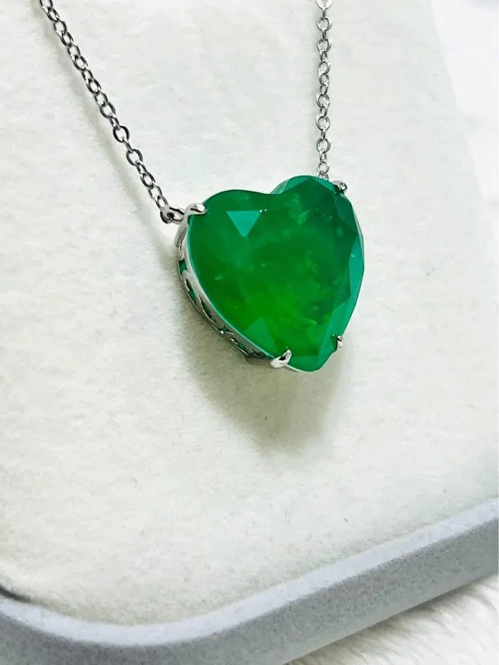 Close-up of a vibrant green Zambian emerald doublet heart pendant with a silver chain.