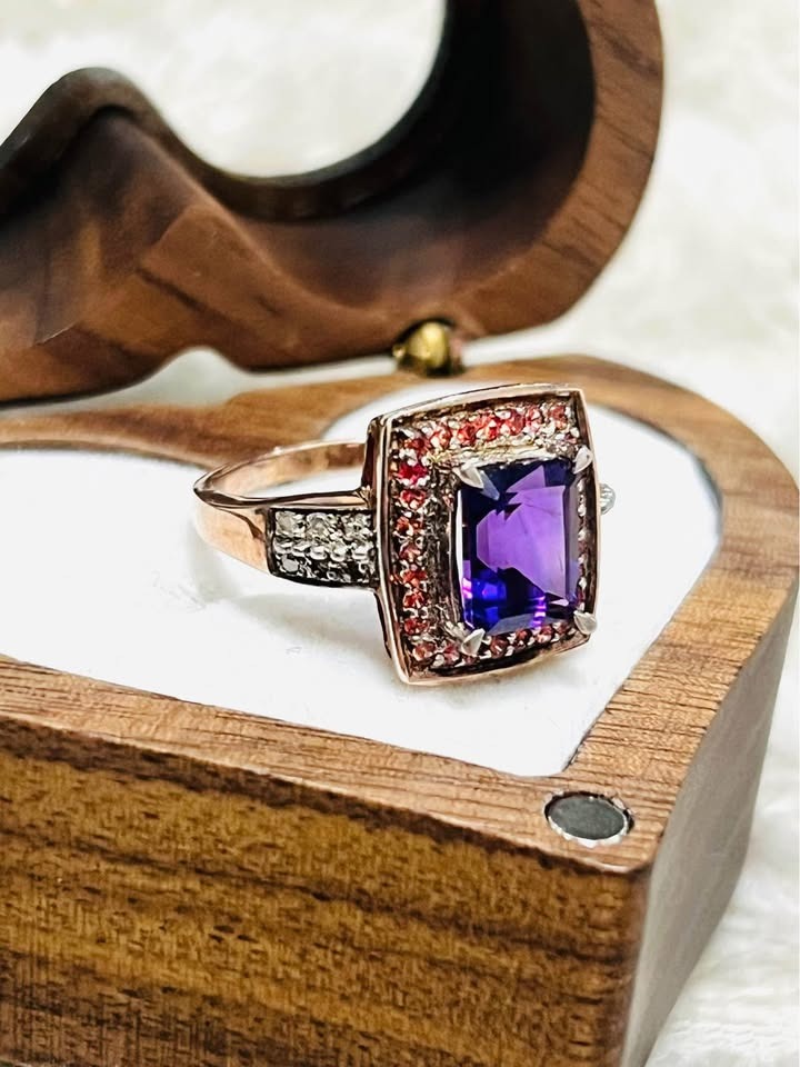 Side view of a stunning emerald-cut natural amethyst ring with red accent stones and diamonds.