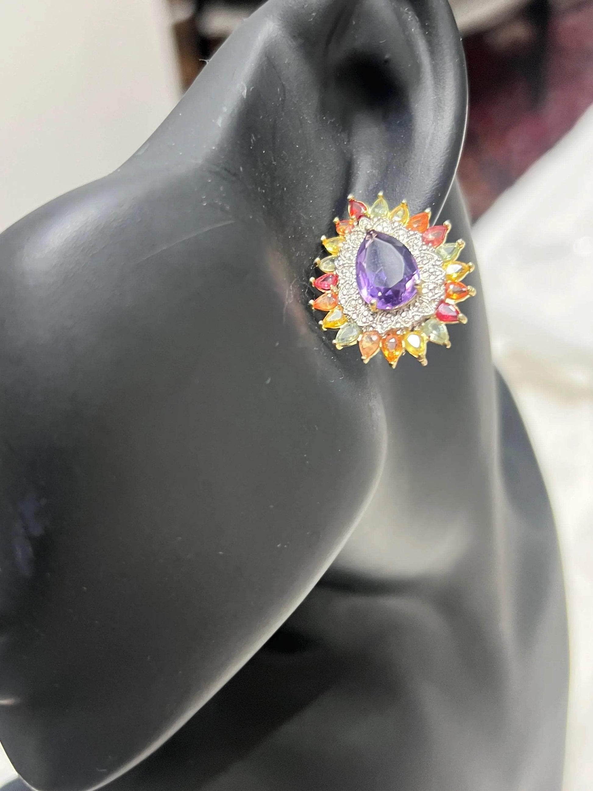 Single handmade amethyst and multi-color sapphire sunburst earring worn on a black ear model, highlighting design.