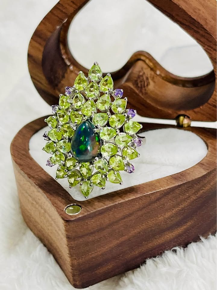 A unique cocktail ring with a mesmerizing black fire opal center, set among peridot and amethyst.