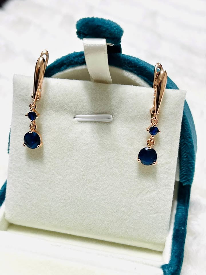 Stunning blue sapphire and rose gold teardrop earrings, showcasing their vibrant color and elegant design in a gift box.