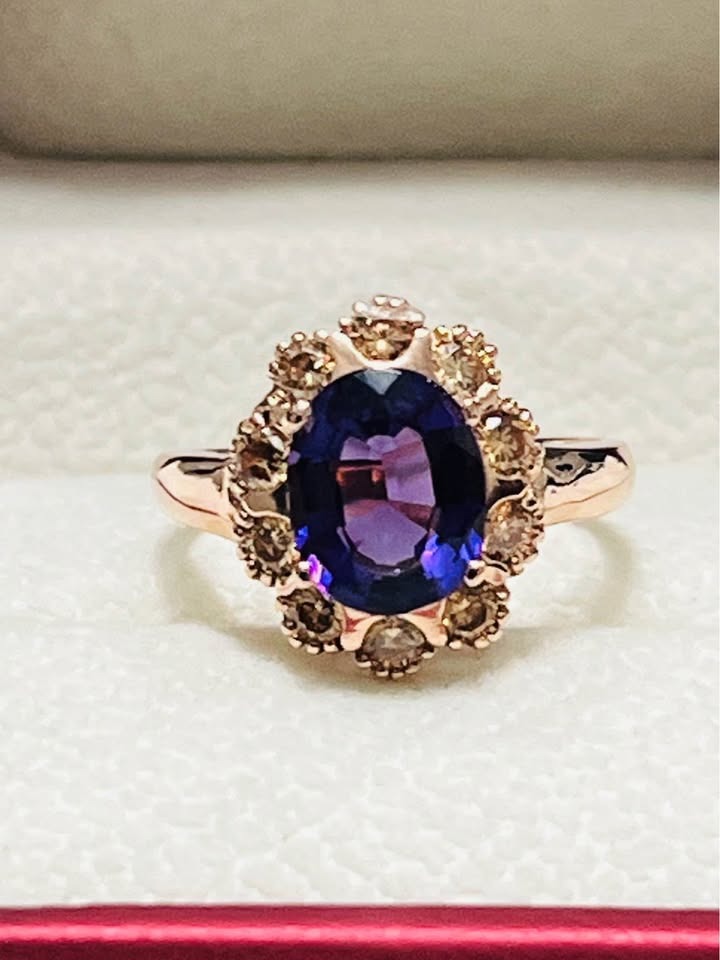  Close-up of a luxurious sterling silver ring with an oval amethyst, framed by a halo of brilliant sapphires, rose gold plated.