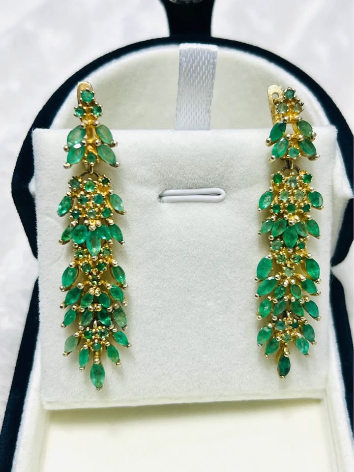 Close-up of natural Colombian emerald earrings, showing the intricate design and vivid green color.