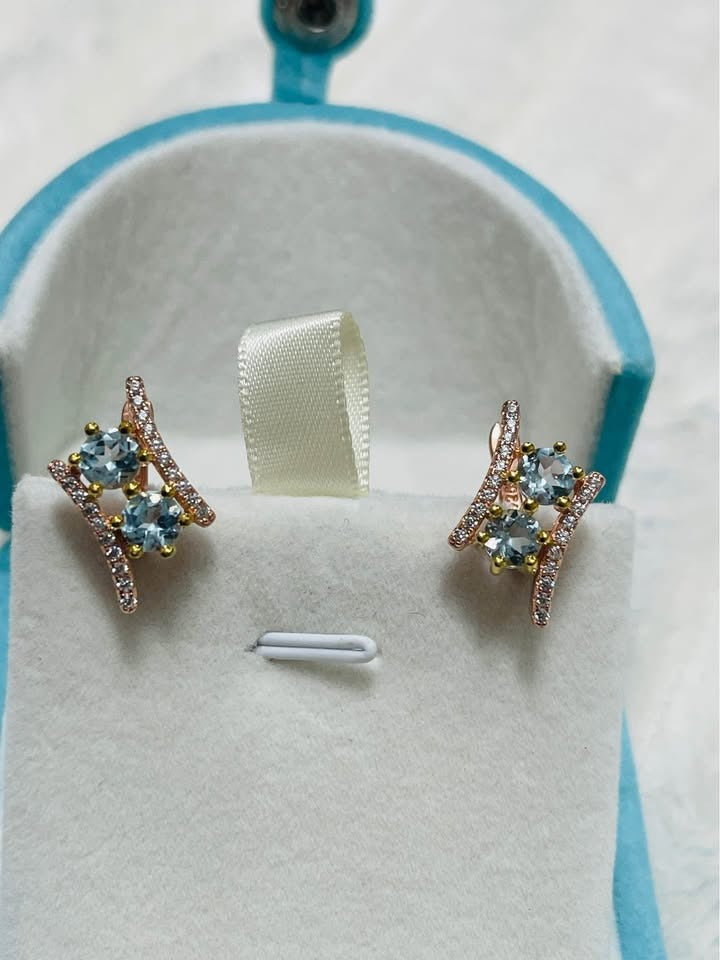 Elegant natural blue topaz earrings with a modern, asymmetrical design, set against a soft background.