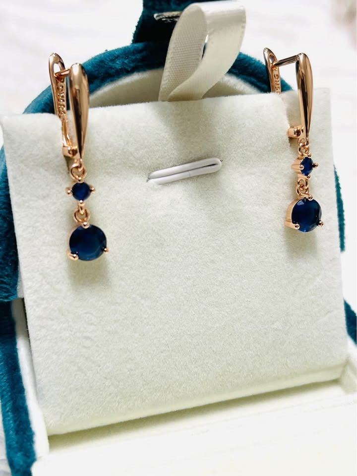 A pair of elegant rose gold earrings with rich blue sapphire gemstones, ideal for adding a touch of sophistication.