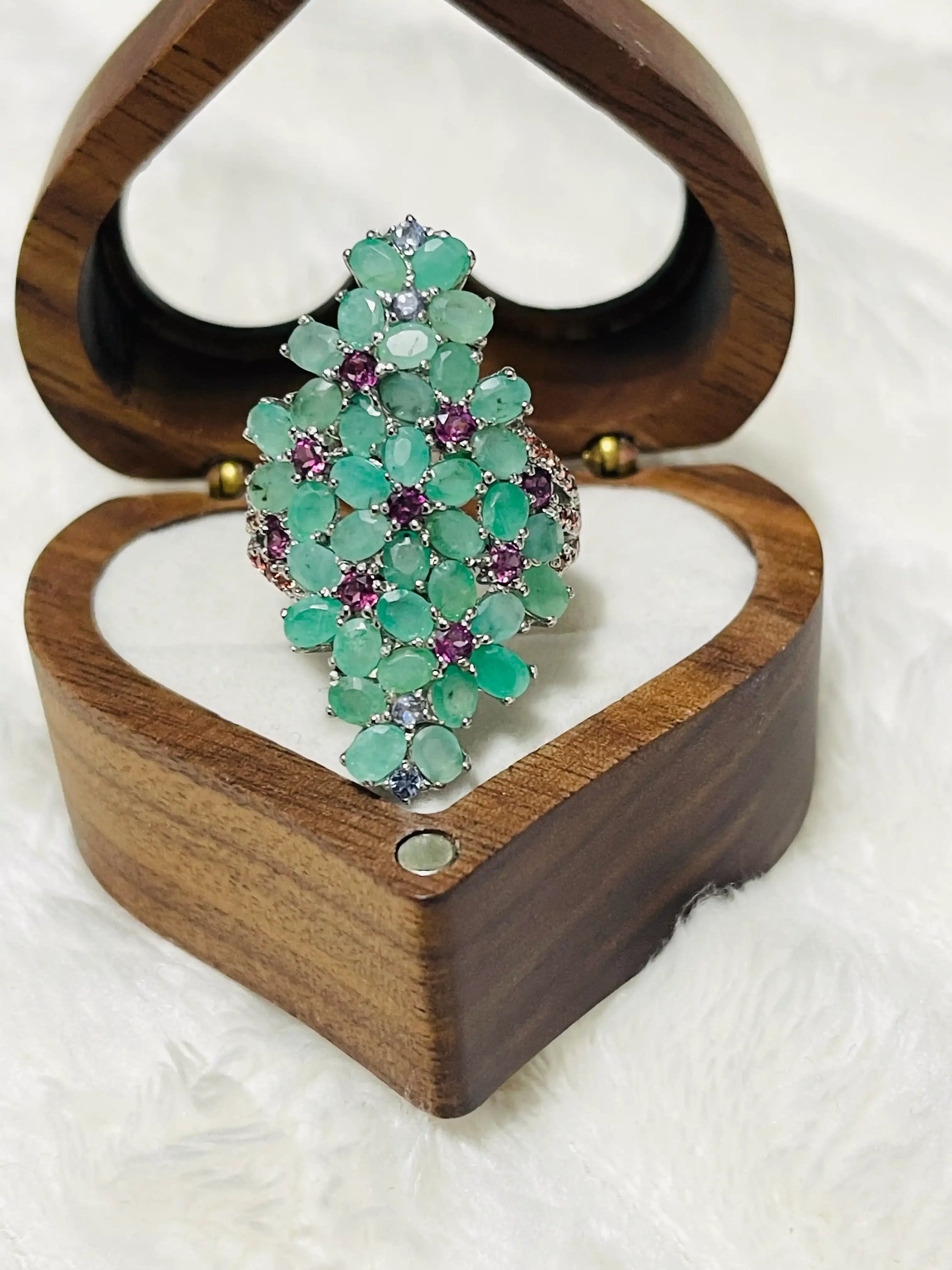 Statement ring with a large cluster of emeralds and amethyst gems, presented beautifully within a wooden heart-shaped box.