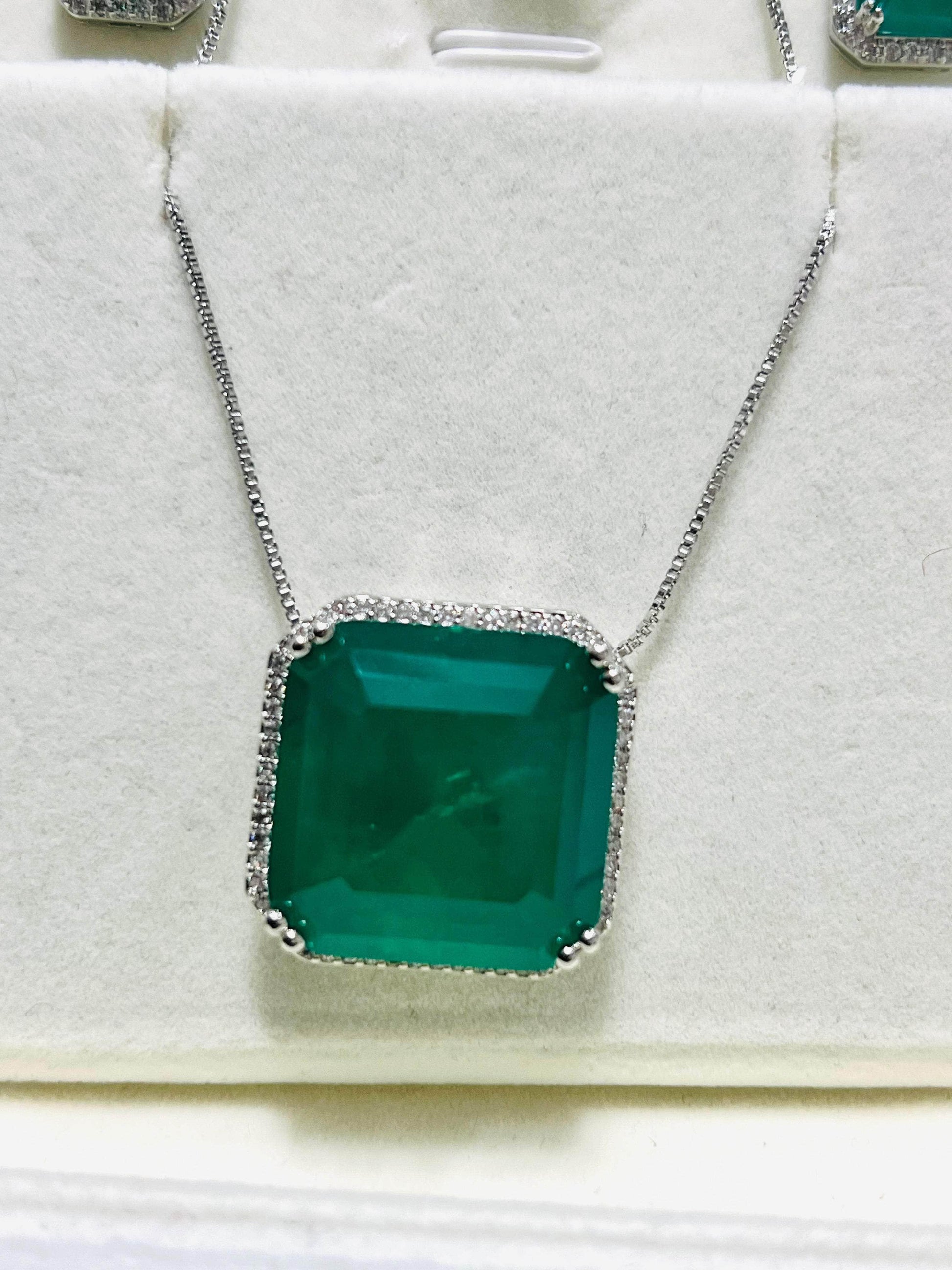 Close-up of a beautiful emerald cut necklace, featuring a vibrant green stone surrounded by a sparkling diamond halo.