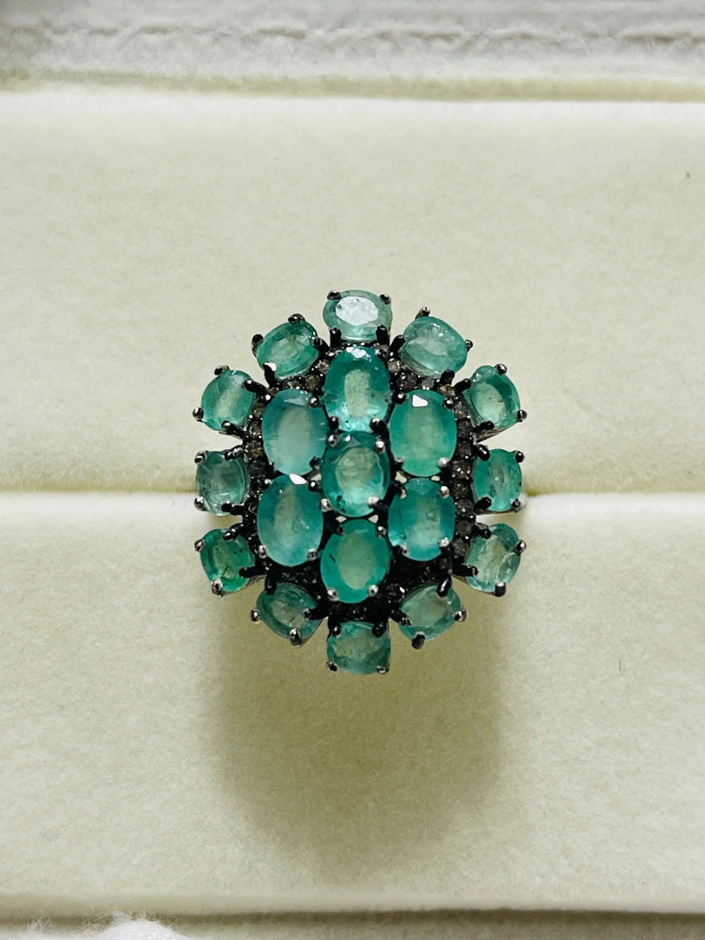 Front view of a vibrant emerald and diamond cluster ring, showcasing its brilliant gemstones and setting.