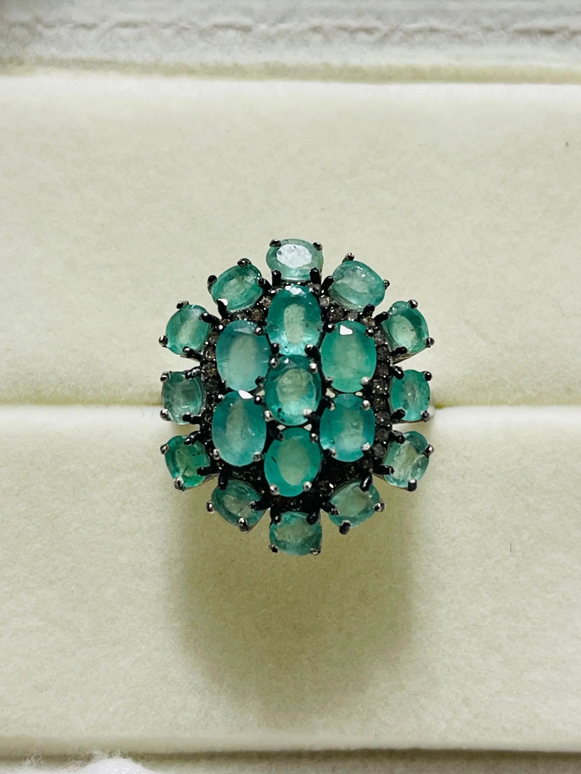 Front view of a vibrant emerald and diamond cluster ring, showcasing its brilliant gemstones and setting.