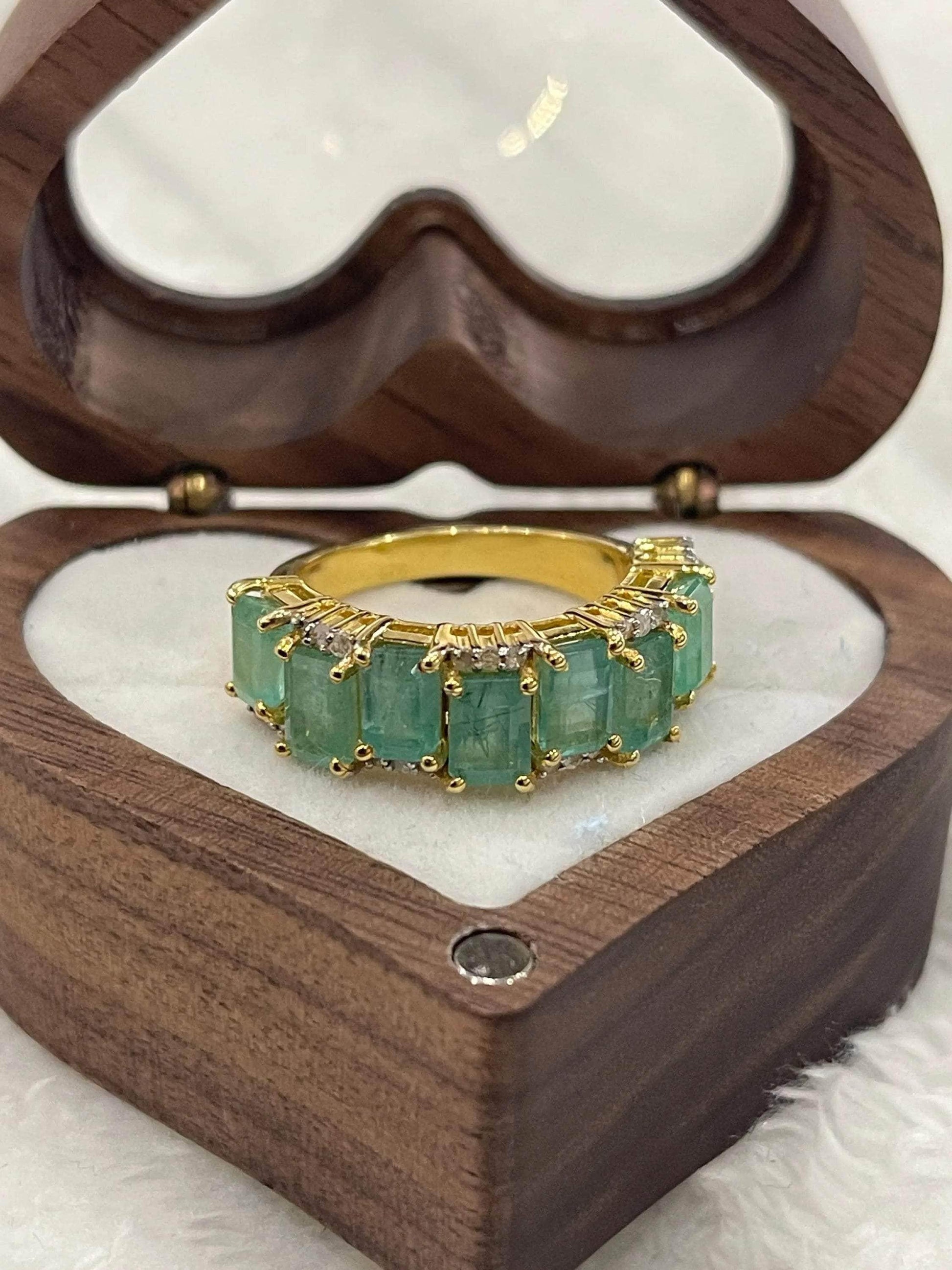  Angled view of a beautiful emerald and diamond flower cluster ring, showcasing its intricate design and sparkle.