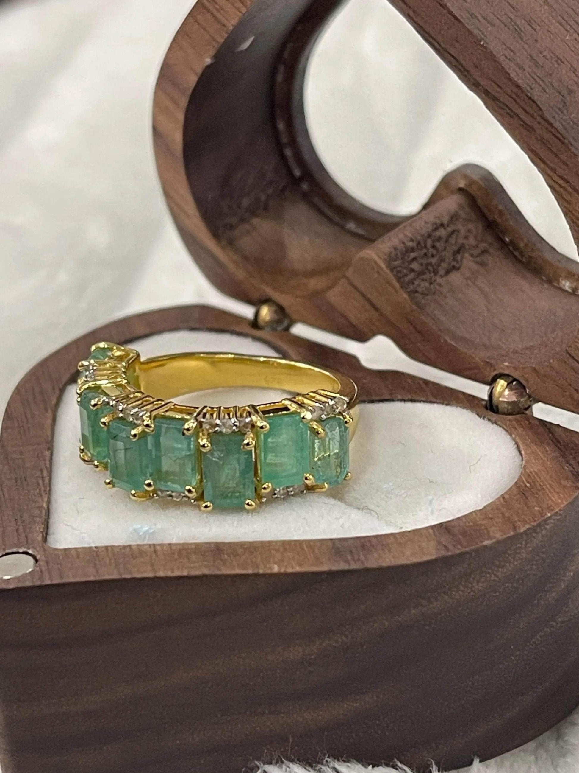 Top-down view of a stunning emerald and diamond flower ring, emphasizing the vibrant green and brilliant facets.