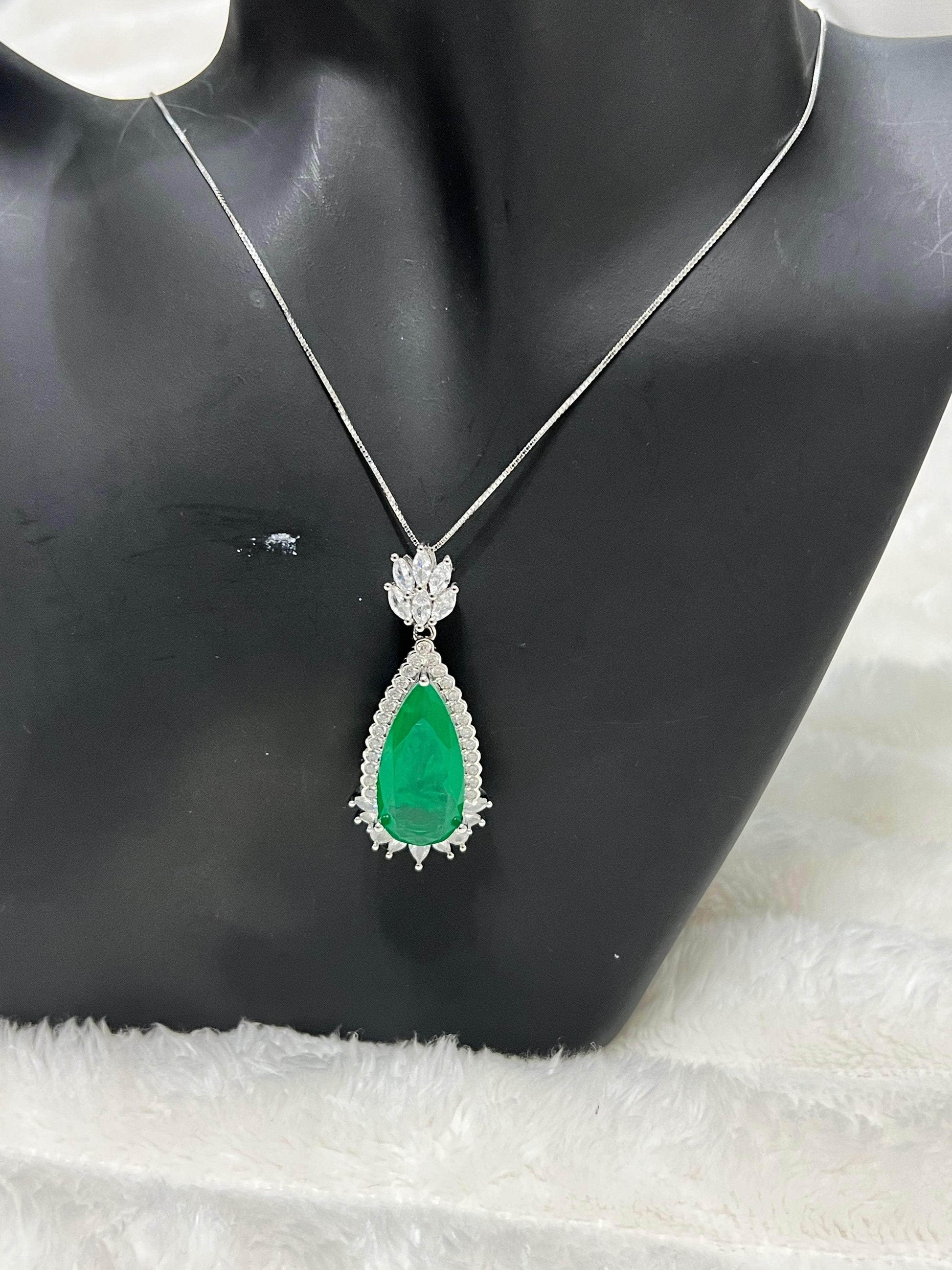 Emerald doublet pendant displayed on a black mannequin, highlighting the striking contrast of green and white stones.
