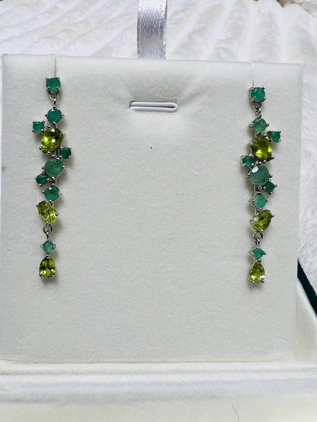  Straight view of beautiful emerald and peridot long drop earrings with various cut green gemstones.