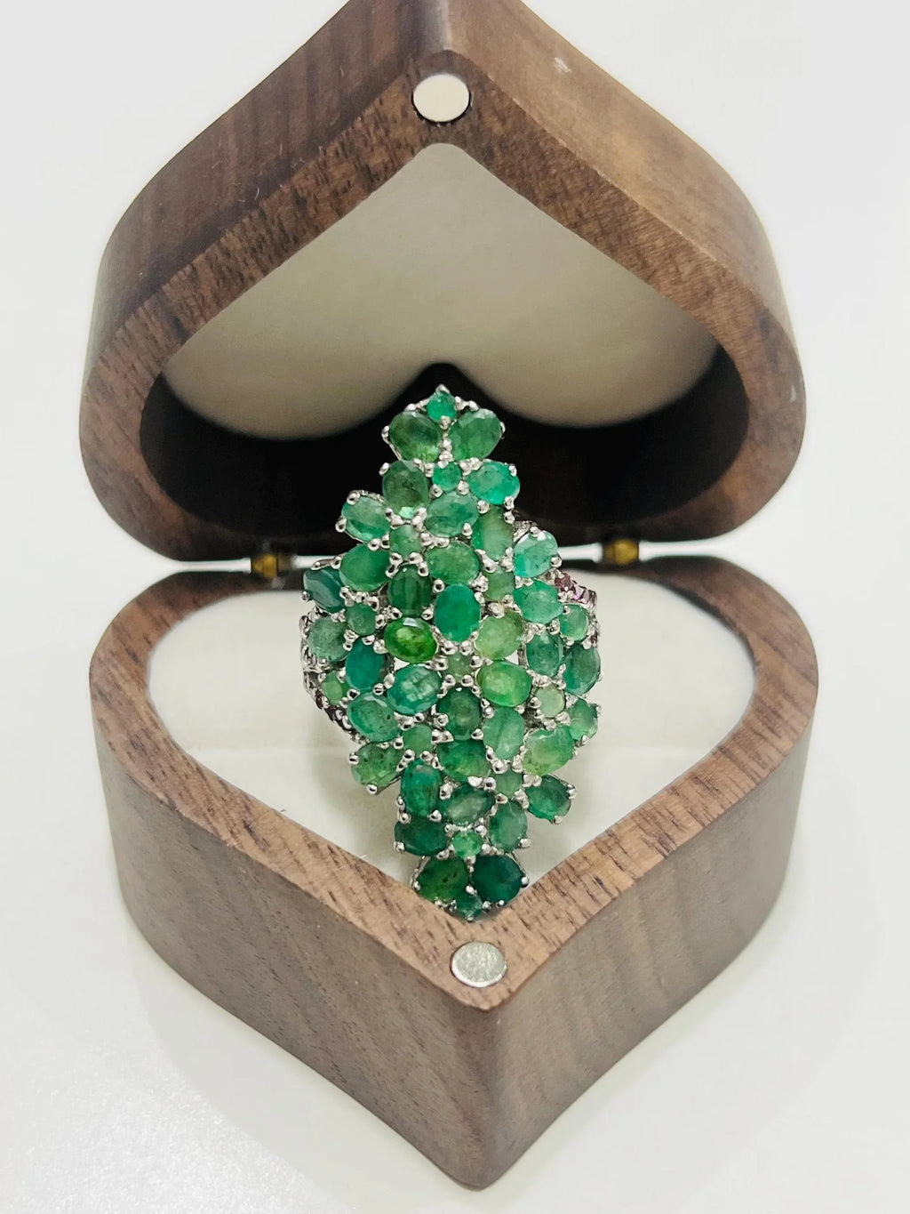 Angled view of a beautiful sterling silver bouquet ring with natural emeralds and rhodolite gemstones.