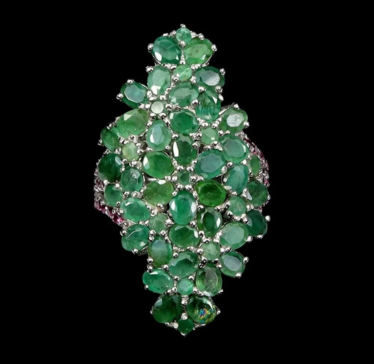 Close-up of an elegant bouquet ring with vibrant emeralds and pink rhodolite garnets on a black display.