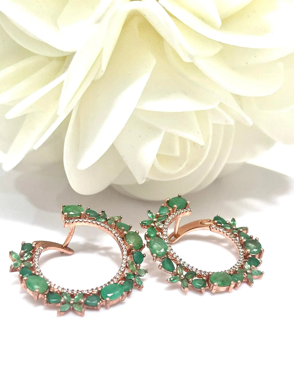 Pair of handmade emerald and rose gold plated hoop earrings on a white surface, angled to show the floral design