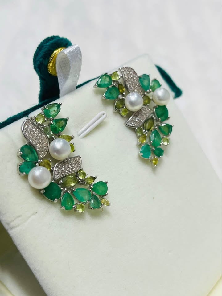 Ear climber style earrings featuring an elegant arrangement of Colombian emeralds, green sapphires, and pearls.