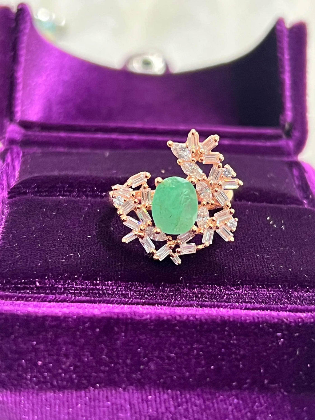 Angled view of a beautiful emerald and sapphire vintage ring, showcasing its intricate details in a velvet box.