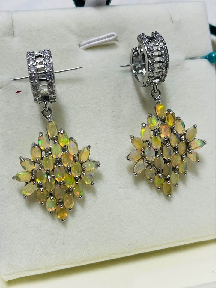Fiery Ethiopian opal earrings suspended from a hoop with baguette-cut white topaz accents.