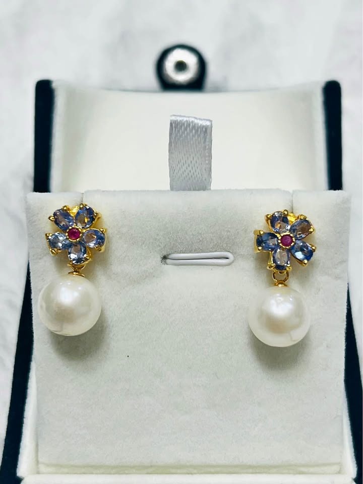 Floral-inspired natural tanzanite and ruby stud earrings with South Sea pearl drops on white display.