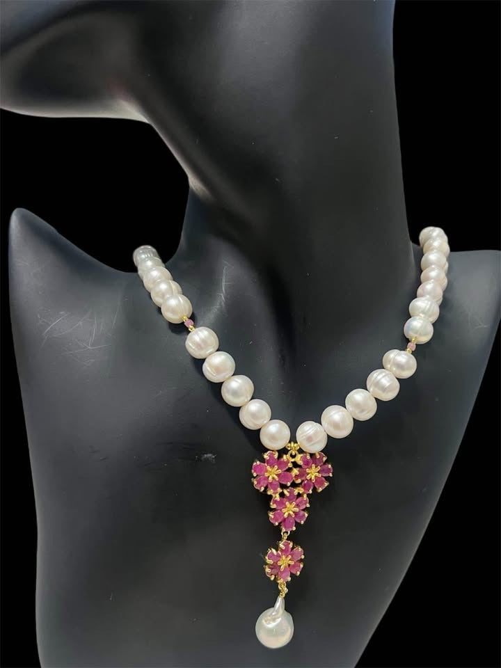 Natural freshwater pearl and ruby flower pendant necklace displayed on a black jewelry mannequin.