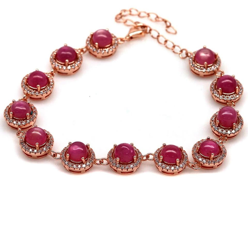 A luxurious rose gold bracelet featuring a line of natural ruby cabochon stones with a halo setting.