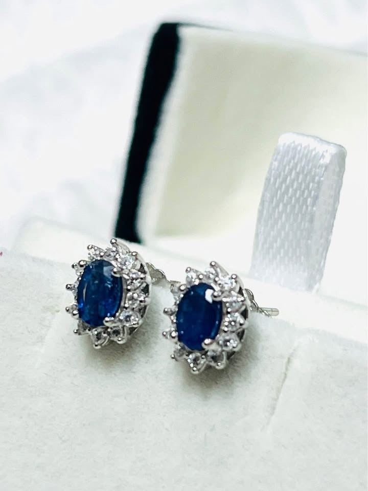 Genuine natural sapphire stud earrings with a brilliant halo setting, viewed from the side.