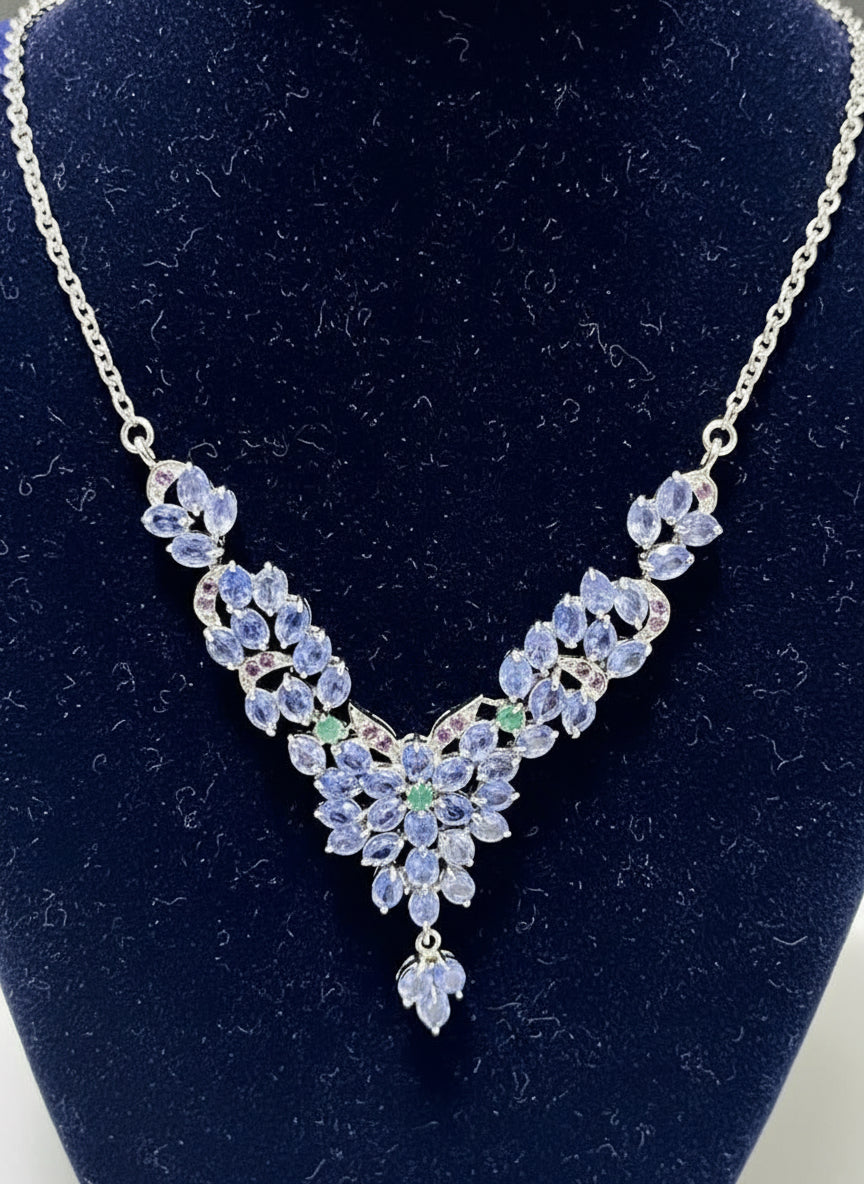 A detailed close-up of a genuine tanzanite and emerald cluster necklace, highlighting the intricate gemstone arrangement.