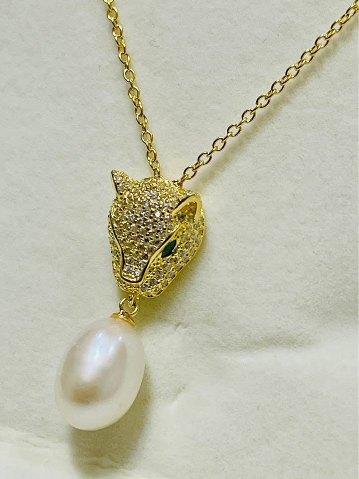 Angled shot of a stunning gold panther necklace with emerald eyes and a luminous South Sea pearl.